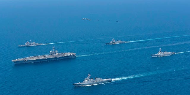 The USS Abraham Lincoln, left, and JS Kongo, front, sail in formation during a U.S.-Japan bilateral exercise at the Sea of Japan on April 12, 2022.