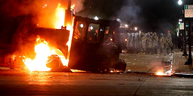 Kenosha County Sherriff and police officers in riot gear form a line behind a burning truck during demonstrations against the shooting of Jacob Blake in Kenosha, Wisconsin on August 24, 2020.