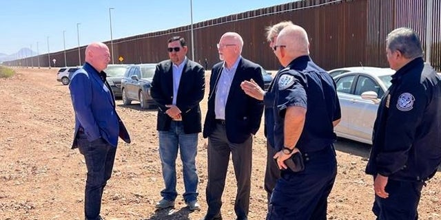 Sen. Mark Kelly of Arizona (at left) meets with U.S. Customs and Border Protection officials at the Douglas Port of Entry along the U.S.-Mexico border, on April 13, 2022