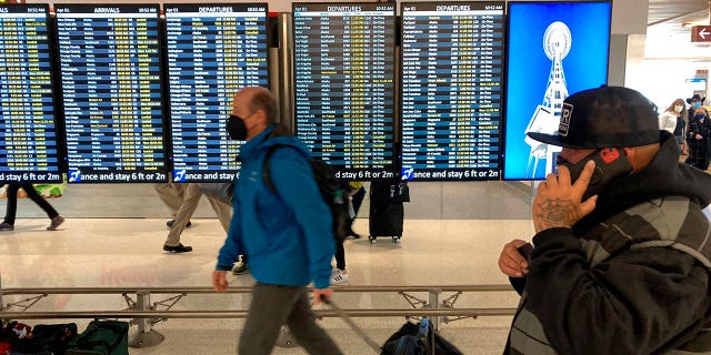 FILE - Travelers walk through Seattle-Tacoma International Airport on Friday, April 1, 2022 in Seattle. On Monday, April 18, 2022, a federal judge in Florida voided the national mask mandate covering airplanes and other public transportation saying it exceeded the authority of U.S. health officials. (AP Photo/Ted S. Warren, File)