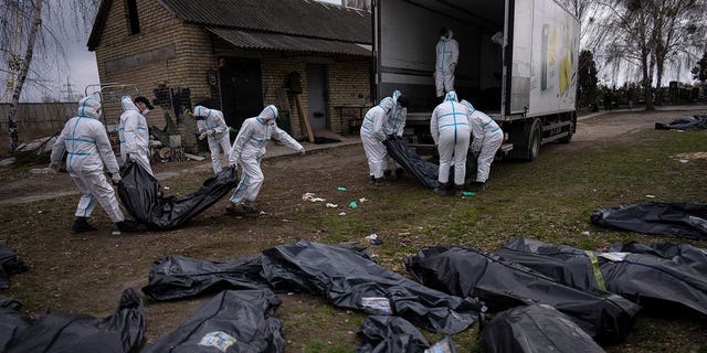 Volunteers load bodies of civilians killed in Bucha onto a truck for transport to a morgue for investigation, in the outskirts of Kyiv, Ukraine, Tuesday, April 12, 2022.