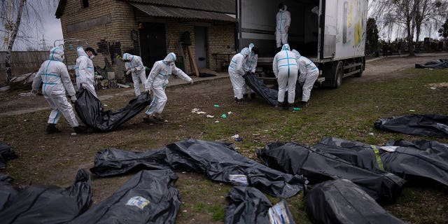 Volunteers load bodies of civilians killed in Bucha onto a truck to be taken to a morgue for investigation, in the outskirts of Kyiv, Ukraine, Tuesday, April 12, 2022. (AP Photo/Rodrigo Abd)