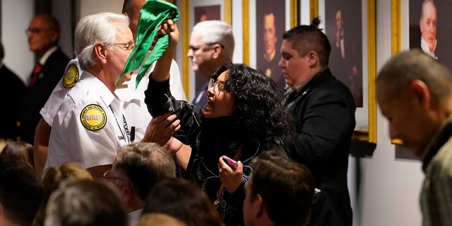 An unidentified pro-choice protester is removed by security as she heckles US Supreme Court Associate Justice Amy Coney Barrett as she meets with Board of Trustees Chairman Frederick J. Ryan, Jr., at the Ronald Reagan Presidential Library Foundation in Simi Valley, Calif. , Monday, April 4, 2022. (AP Photo/Damian Dovarganes)