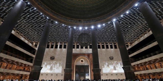 Indonesian Muslims pray spaced apart as they practice social distancing to curb the spread of the new coronavirus during an evening prayer called "tarawih" marking the first eve of the holy fasting month of Ramadan at Istiqlal Mosque in Jakarta, Indonesia, April 12, 2021. 