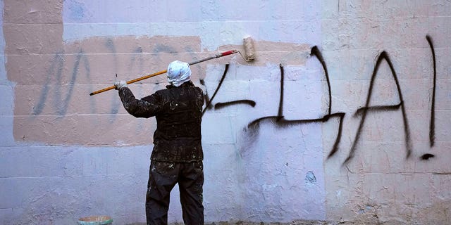 2022年3月18日，一名工人在俄罗斯圣彼得堡一栋公寓楼的墙上涂鸦上写着“是的，和平！”。