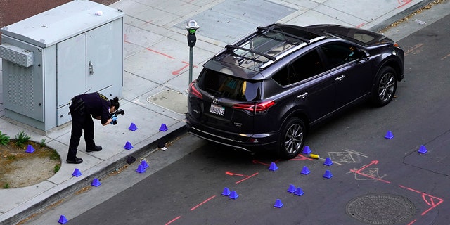 A crime scene investigator photographs evidence markers at the scene of a mass shooting In Sacramento, Calif. April 3, 2022.
