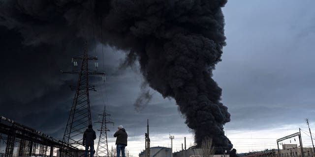 People watch as smoke rises in the air after shelling in Odesa, Ukraine, Sunday, April 3, 2022.