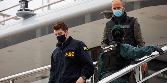 A U.S. federal agent walks past two Civil Guards on the yacht called Tango in Palma de Mallorca, Spain, Monday April 4, 2022. 