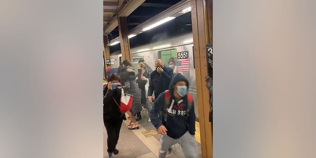 Passengers run from a subway car in a station in the Brooklyn, New York, Tuesday, April 12, 2022.