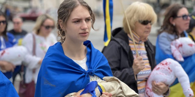 Woman carries fake blood-stained sack, representing the children killed in the war in Ukraine
