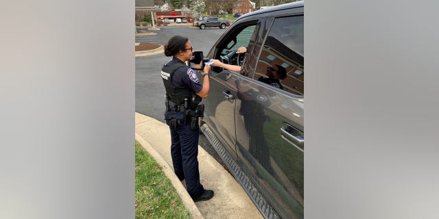 Officer Johnna Sylvester having stopped a vehicle and providing the "report card" to the citizen she stopped. Photo provided by Warrenton Police Department.