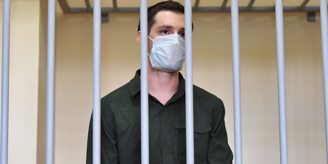 特雷弗·里德, charged with attacking police, stands inside a defendants' cage during his verdict hearing at Moscow's Golovinsky district court on July 30, 2020.