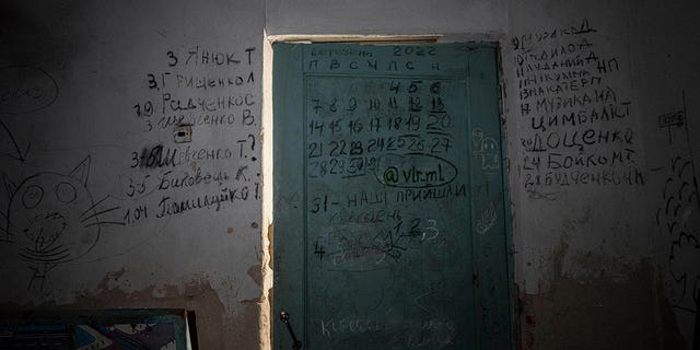 Writing can be seen on a wall and a door in the basement of a school in Yahidne, near Chernihiv, Ukraine, Tuesday, April 12, 2022.