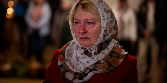 Olga Zhovtobrukh, 55, cries during an Easter service celebrated at a church in Bucha on the outskirts of Kyiv, Sunday, April 24, 2022.