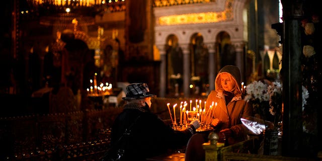 Worshippers light candles at St. Volodymyr's Cathedral during Orthodox Easter celebrations in Kyiv, Ukraine, Sunday, April 24, 2022. 