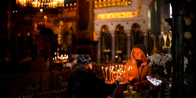 Worshippers light candles at St. Volodymyr's Cathedral during Orthodox Easter celebrations in Kyiv, Ukraine, Sunday, April 24, 2022. 