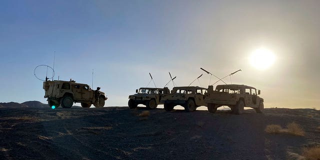 Army vehicles on the ridge, as soldiers from the 2nd Brigade, 1st Cavalry Division, prepare to attack the enemy in the town nearby, during an early morning training exercise at the National Training Center at Fort Irwin, Calif., April 12, 2022. 