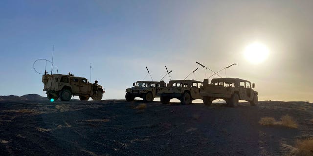 Army vehicles on the ridge, as soldiers from the 2nd Brigade, 1st Cavalry Division, prepare to attack the enemy in the town nearby, during an early morning training exercise at the National Training Center at Fort Irwin, Calif., April 12, 2022.