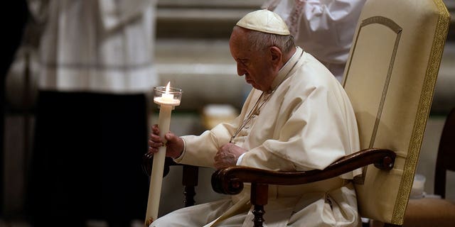 Pope Francis holds a Paschal candle as he presides over a Easter vigil ceremony in St. Peter's Basilica at the Vatican, Saturday, April 16, 2022.