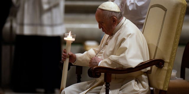 Pope Francis holds a Paschal candle as he presides over a Easter vigil ceremony in St. Peter's Basilica at the Vatican, Saturday, April 16, 2022.