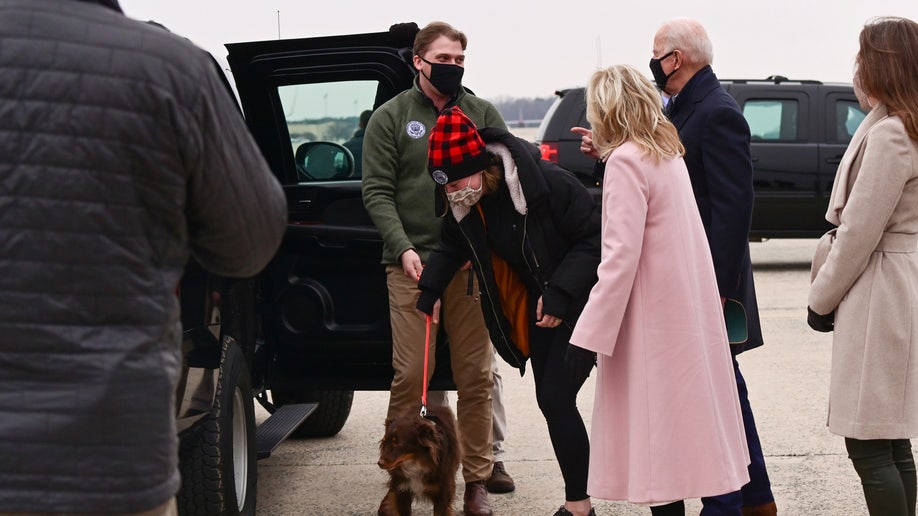 U.S. President Joe Biden and first lady Jill Biden look on as Biden's granddaughter Naomi and her boyfriend Peter Neal manage Naomi's dog after a trip to Camp David, at Joint Base Andrews, Maryland, U.S., February 15, 2021. 
