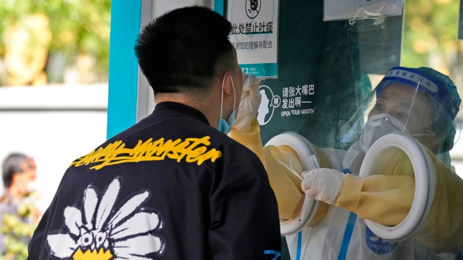 A worker takes a swab sample at a Beijing COVID-19 test center