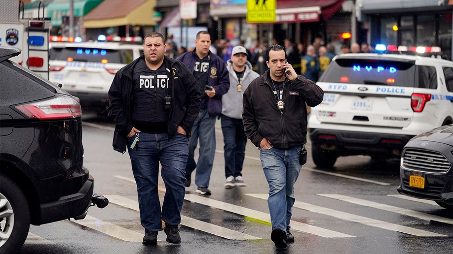 New York City Police Department personnel gather at the entrance to a subway stop in the Brooklyn borough of New York, Tuesday, April 12, 2022. (AP Photo/John Minchillo)