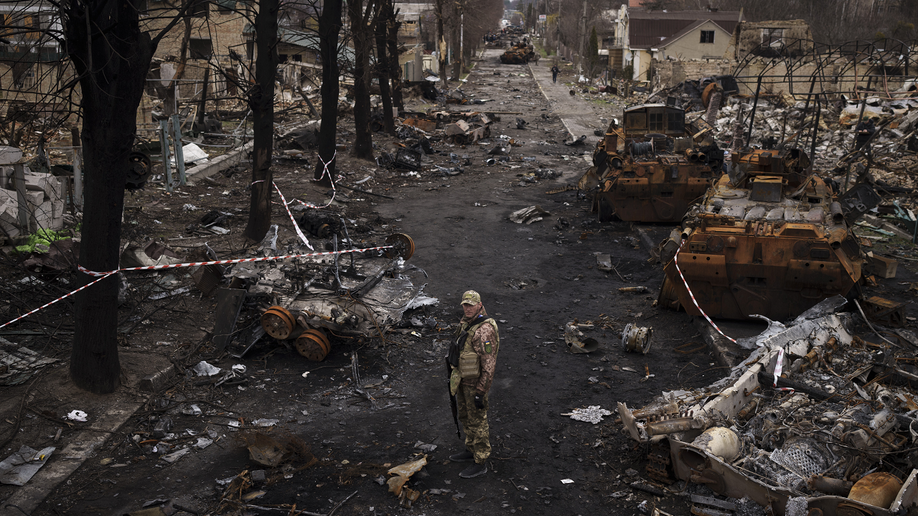 Ukrainian soldier stands amid destroyed Russian tanks