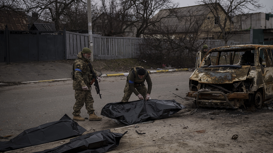 Ukrainian soldiers recover remains of civilians killed in the war