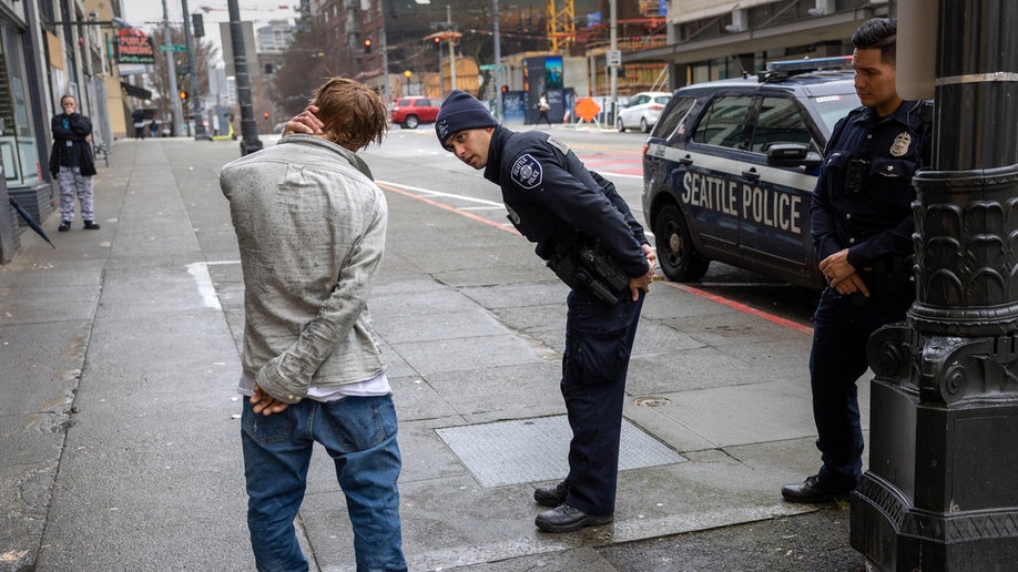 Police officers check on a man who said he has been smoking fentanyl in downtown Seattle on March 14, 2022 in Seattle, Washington. Use of the powerful opioid has surged in the last several years, especially in Seattle's large homeless community. According to a recent report commissioned by Seattle Councilmember Andrew Lewis, the COVID-19 pandemic put undue pressure on the city's shelter system and delayed funds for new housing, leading to an increase in homelessness