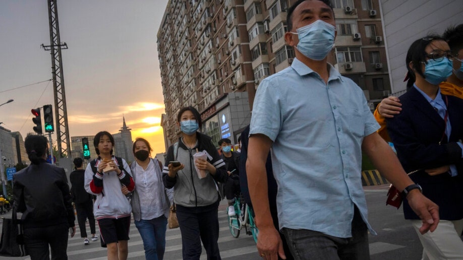 People wearing masks cross a Beijing intersection