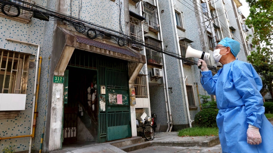 A man with a megaphone talks to locked down Shanghai residents