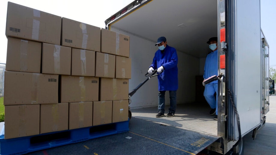 Workers in Shanghai load boxes of vegetables onto trucks