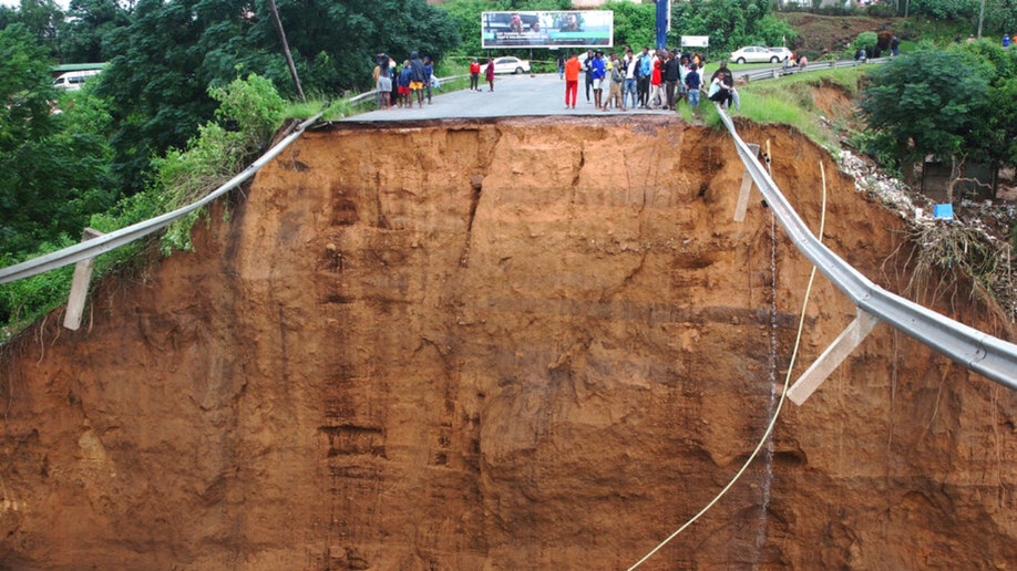 People stand above where a bridge was swept away in Ntuzuma
