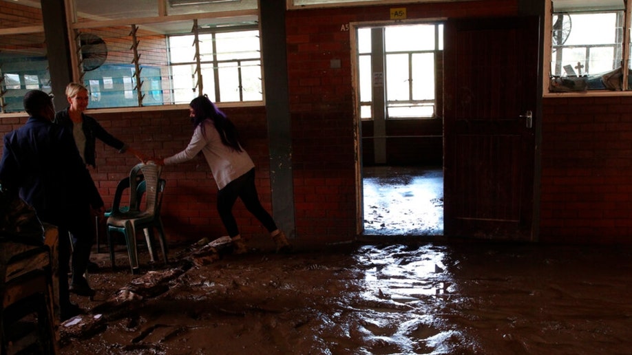 Teachers and students work to clear mud from flooding inside a Durban classroom