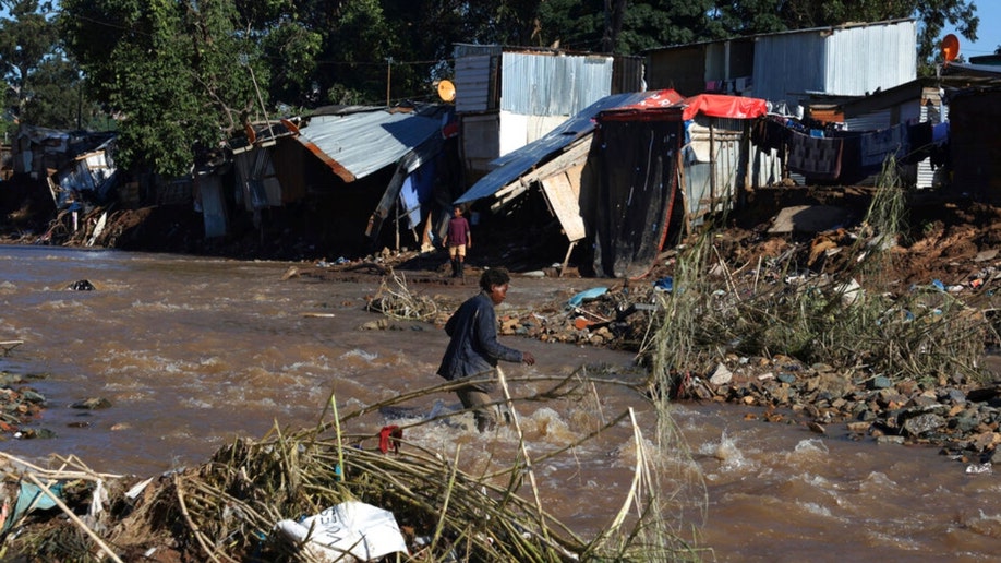 A man crosses an informal settlement during flooding in Burban