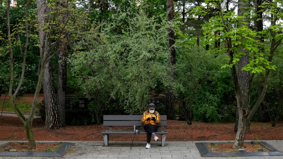 A man wearing a face mask sits on a bench in South Korea