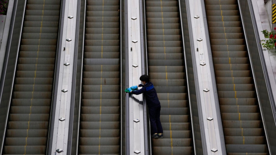 A woman wearing a face mask cleans an escalator in South Korea