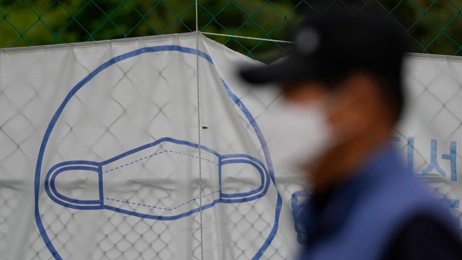 A South Korean man wearing a face mask walks by a poster with a mask on it