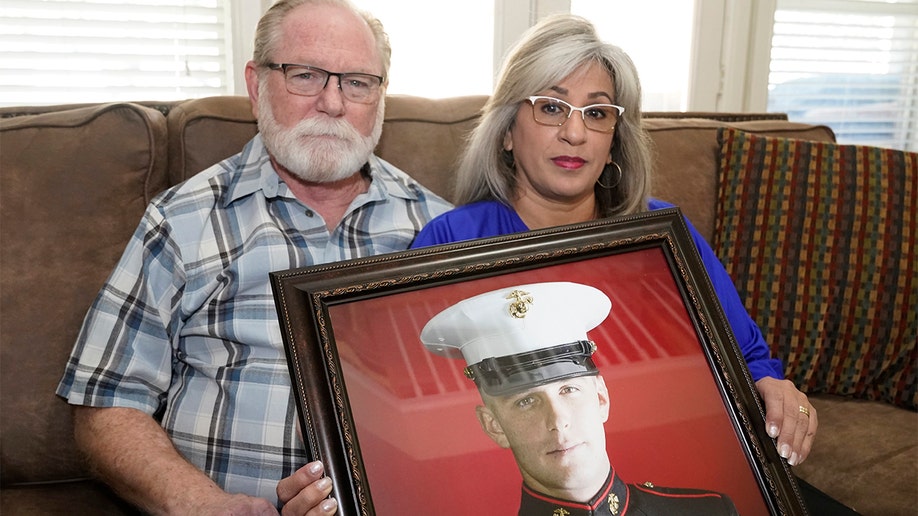 FILE - Joey and Paula Reed pose for a photo with a portrait of their son Marine veteran and Russian prisoner Trevor Reed at their home in Fort Worth, Texas, Feb. 15, 2022. (AP Photo/LM Otero, File)