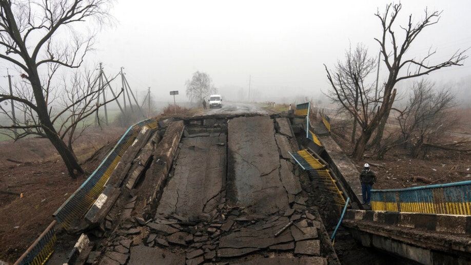 A man standing next to a destroyed bridge on the outskirts of Kyiv.