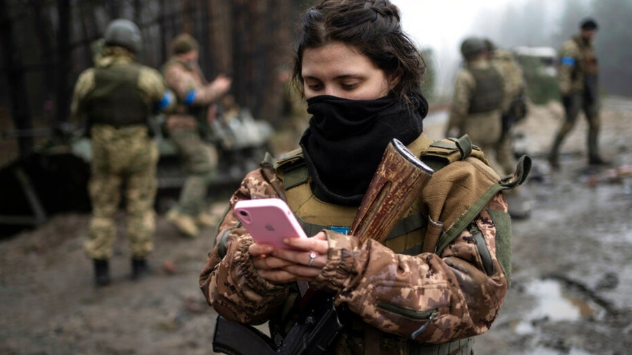 A Ukrainian army soldier checks her phone.