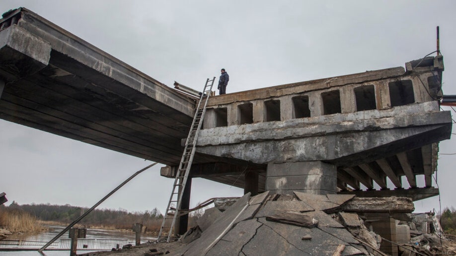 A Ukrainian serviceman stands on a destroyed bridge between Dytiatky and Chernobyl
