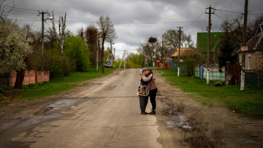 Neighbors hug during a funeral service in Bucha