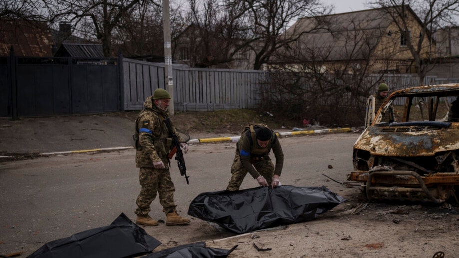 Ukrainian soldiers recover the remains of four civilians in Bucha
