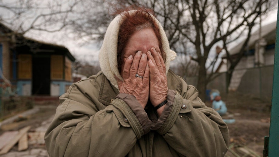 A woman cries in front of her house in Andriivka