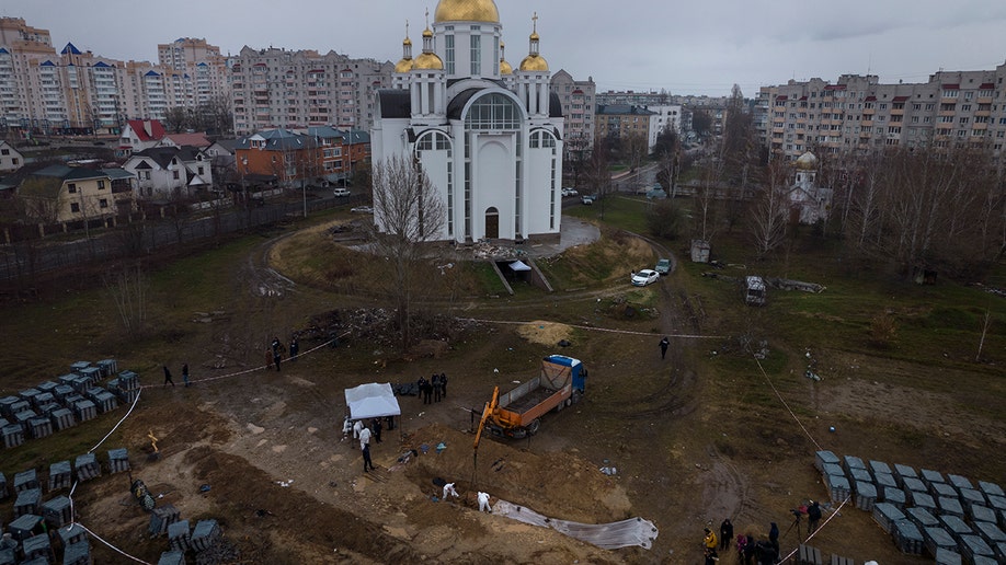 Cemetery workers work at a mass grave in Bucha, on the outskirts of Kyiv, Ukraine, to identify civilians killed during the war against Russia, Sunday, April 10, 2022.