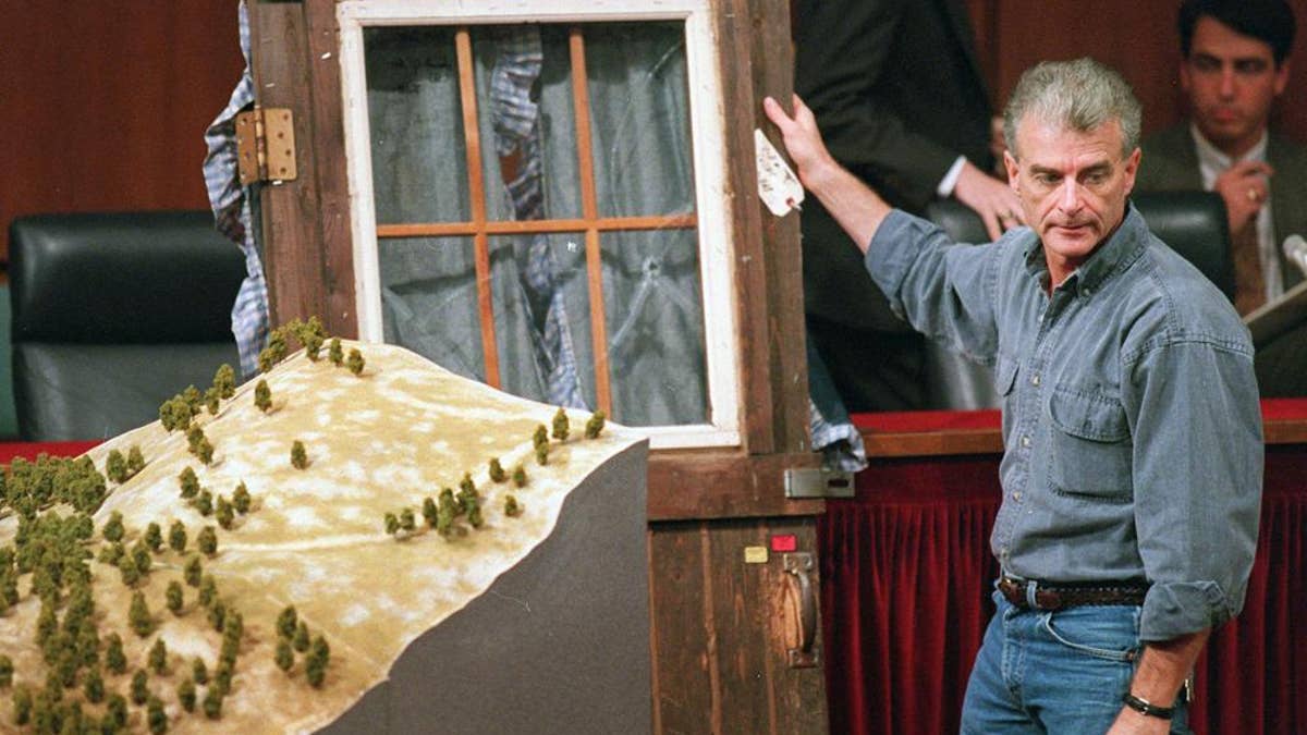 Randy Weaver holds the door of his cabin showing holes from bullets fired during the 1992 siege of his Ruby Ridge, Idaho, home, model at left, during testimony before the Senate Judiciary Subcommittee on Capitol Hill in Washington on Sept. 6, 1995.