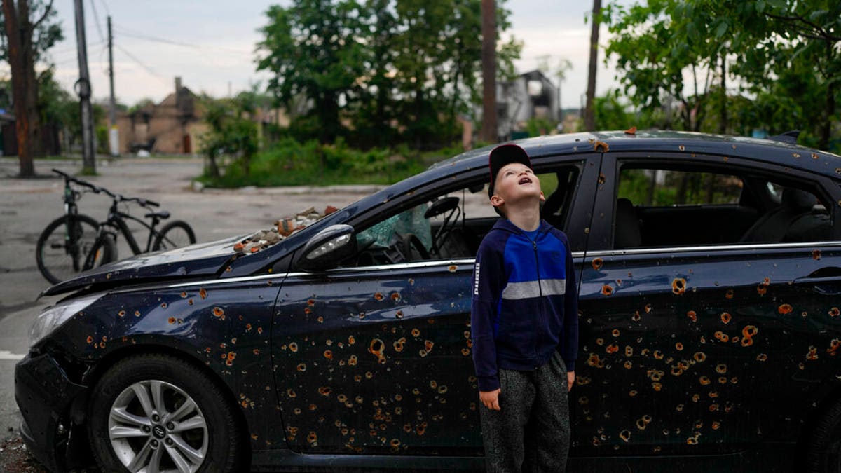 Child stands next to damaged car