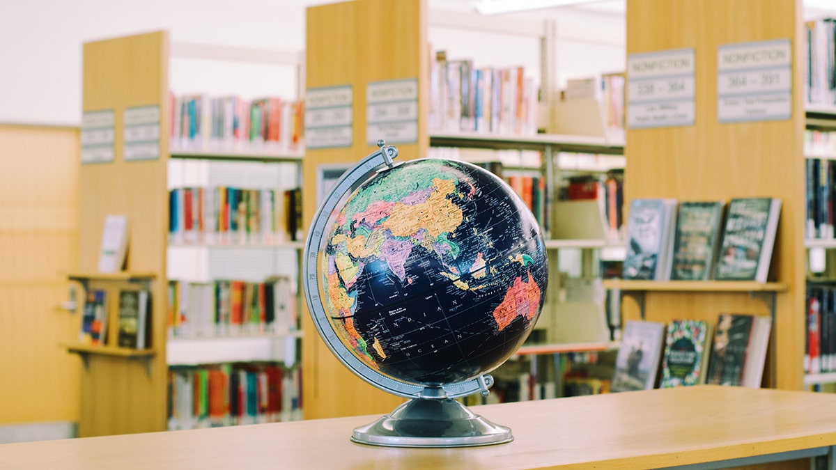 globe on desk in library, stacks in background